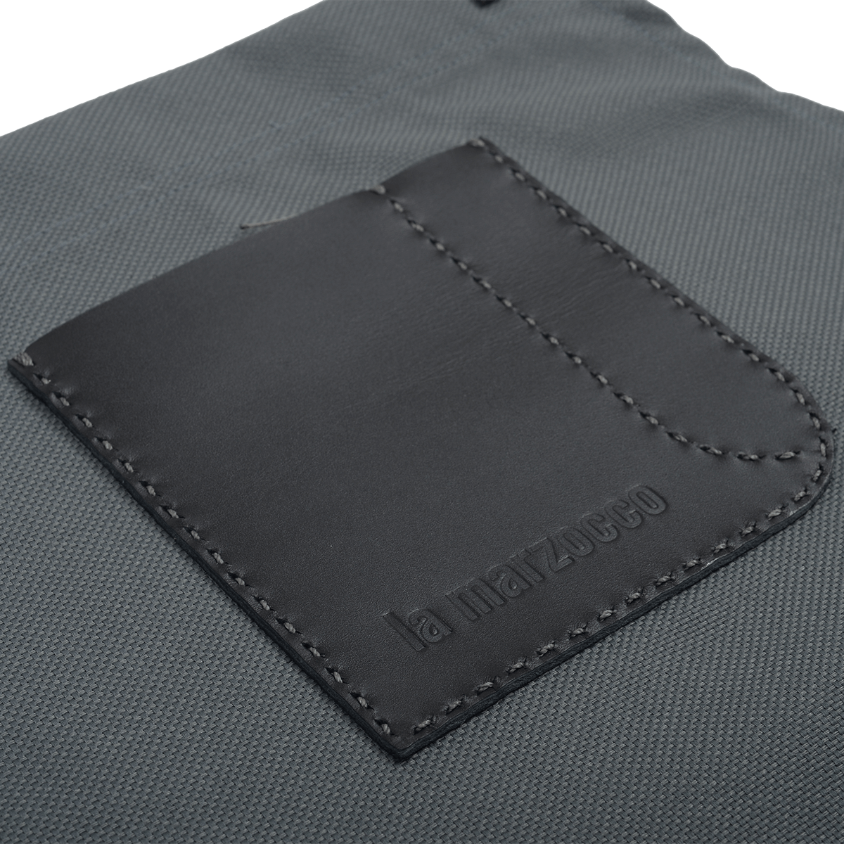 Detailansicht der La Marzocco Barista-Schürze aus robustem, wasserdichtem Segeltuch mit hochwertiger Lederapplikation.